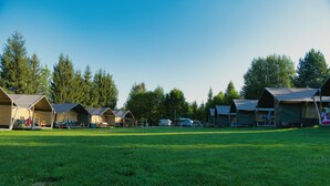 A campground with multiple tents, a grassy field, and trees in the background. - Getaway for 5 With Private Terrace (Janův Důl)
