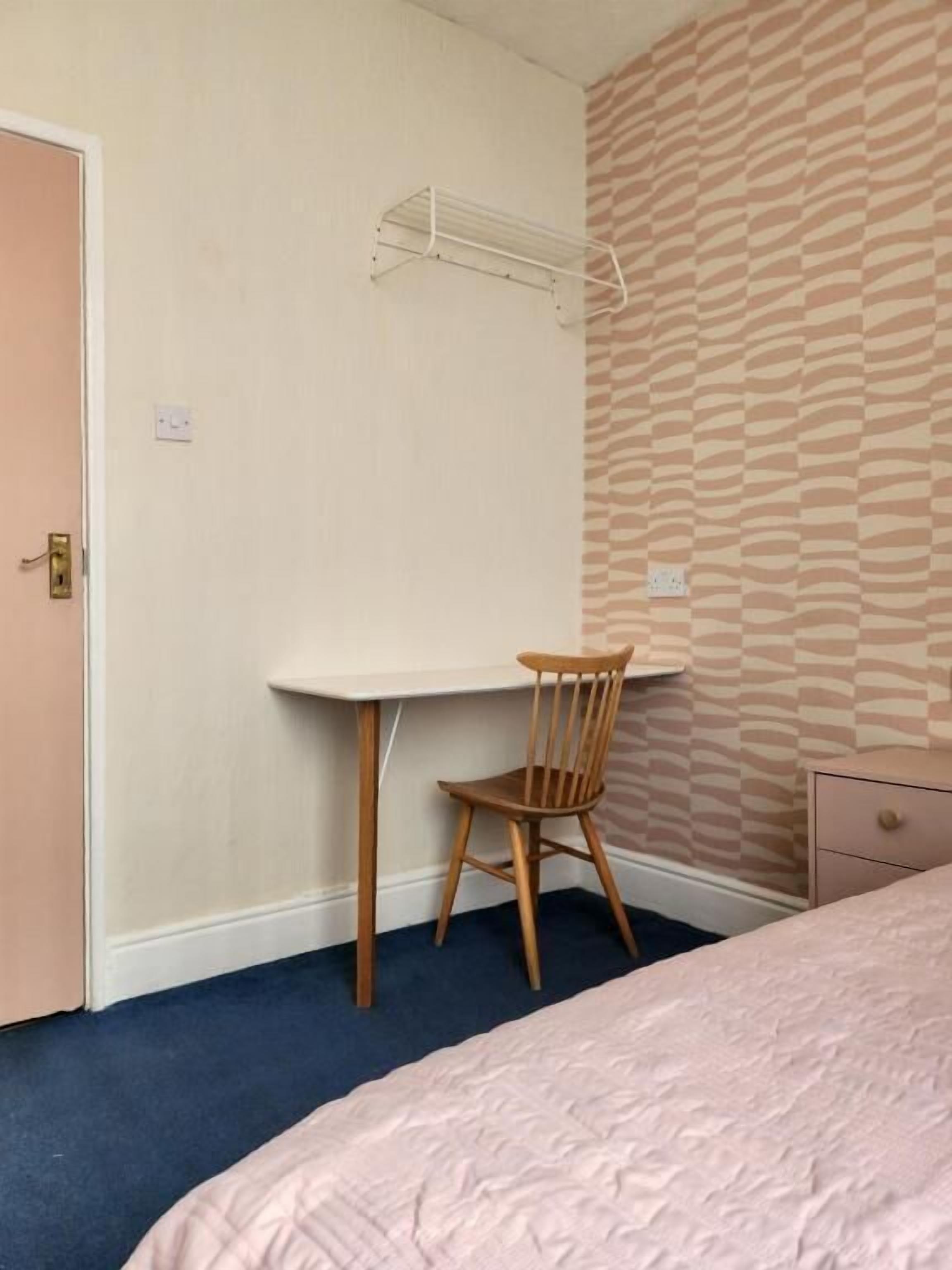 A bedroom with a bed, a desk, and a chair.