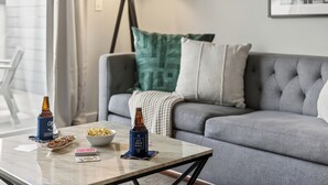 A living room with a sofa, a coffee table, a lamp, and a framed picture on the wall. - ADA Unit | Rooftop Lounge | Walk to Vanderbilt + Music Row | Hillsboro Village (Nashville)