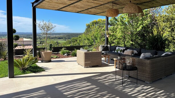 An outdoor patio with a covered seating area, a view of the countryside, and a pergola structure. - Contemporary Villa with Unobstructed View & Pool (Éguilles)
