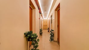 A hotel hallway with a tiled floor, wooden doors, and potted plants. - Classic Hotel Venkateshwara (Kolkata)