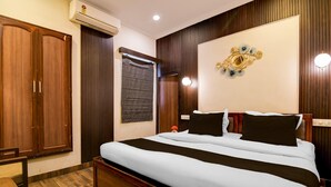 A bedroom with a large bed, wooden wardrobe, and a wall-mounted air conditioner. - Classic Hotel Venkateshwara (Kolkata)