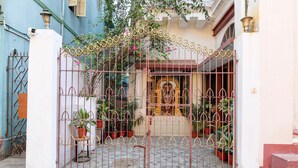 A gated entrance with a decorative metal gate, potted plants, and a small shrine. - Classic Hotel Venkateshwara (Kolkata)