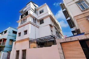Un immeuble à plusieurs étages doté d’un balcon, d’une porte de garage et surplombant un ciel bleu dégagé.