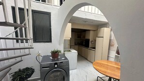 Un área de lavandería compacta con lavadora, una mesita y una planta en maceta.