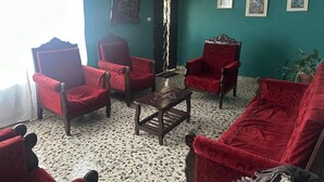 Una habitación con paredes verde azulado, piso estampado y sillas tapizadas en rojo.