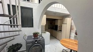 A compact laundry area with a washing machine, a small table, and a potted plant.