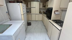 A compact kitchen with white cabinets, a gas stove, a refrigerator, and a microwave.