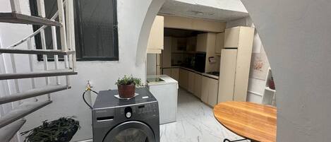 A compact laundry area with a washing machine, a small table, and a potted plant.