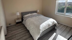 A bedroom with a bed, bedside lamps, a window with a view, and a radiator. - Spacious 3-Bed Home at the heart of Sheffield S2 (South Yorkshire)
