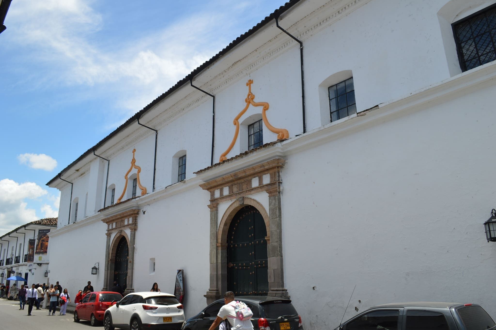 A building with white walls, large arched windows, and a black door with decorative elements.