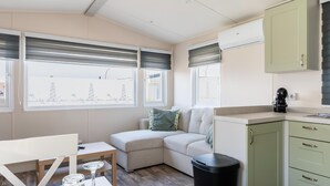 Una habitación acogedora con sofá, una mesita, un cubo de basura y una kitchenette.