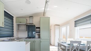 Una cocina compacta con estufa a gas, un lavamanos y alacenas.