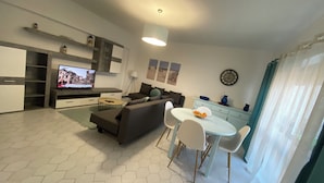 Una sala de estar moderna con un sofá, televisión, mesa de comedor y sillas.