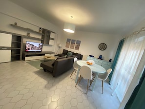 Ein modernes Wohnzimmer mit einer Couch, Fernseher, Esstisch und Stühlen.