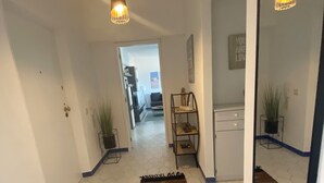 Un pasillo con suelo de baldosas hexagonales, un espejo, una lámpara colgante y una alfombra.