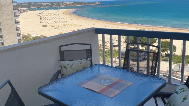 Un balcón con mesa y sillas que da a la playa.