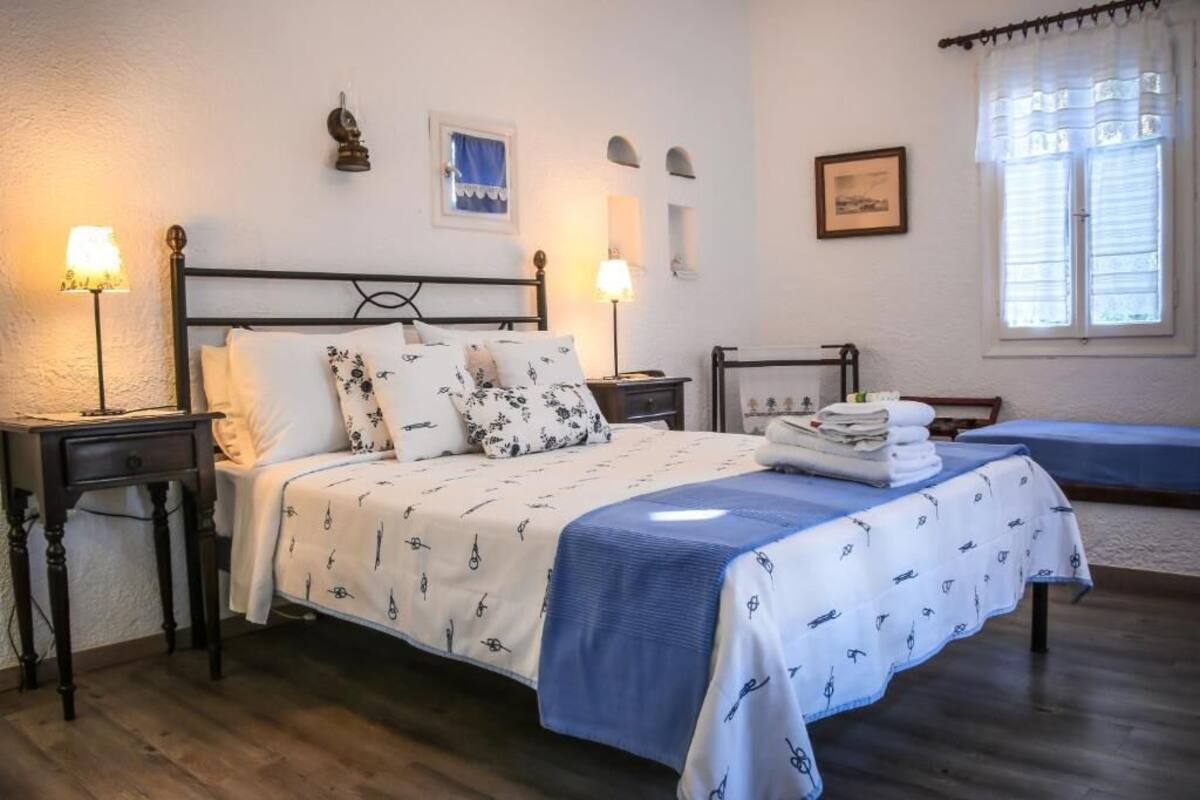 A bedroom with a bed, bedside tables, a lamp, a window with curtains, and a wall-mounted picture.