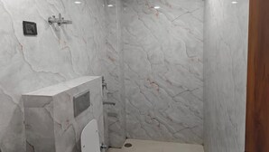 Kylpyhuone, jossa on marmoriseinät, wc ja suihkutila.