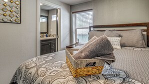 Ein Schlafzimmer mit einem gemusterten Bettbezug, einem hölzernen Kopfteil und einem gewebten Korb auf dem Bett.