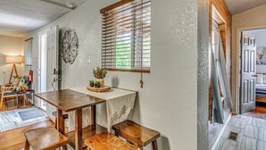 Ein Essbereich mit einem Holztisch, Bänken, einem Wanddekor und einem Fenster mit Jalousien.