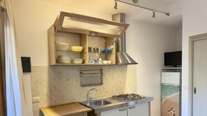 A compact kitchen with a gas stove, sink, and a small countertop. - Residence Abbaechelu Santa Margherita (Pula)