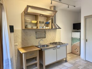A compact kitchen with a gas stove, sink, and a small countertop. - Residence Abbaechelu Santa Margherita (Pula)