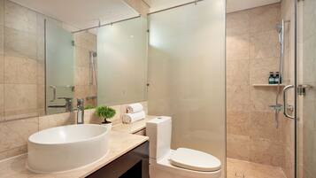 A modern bathroom with a large oval sink, a toilet, and a glass-enclosed shower area.