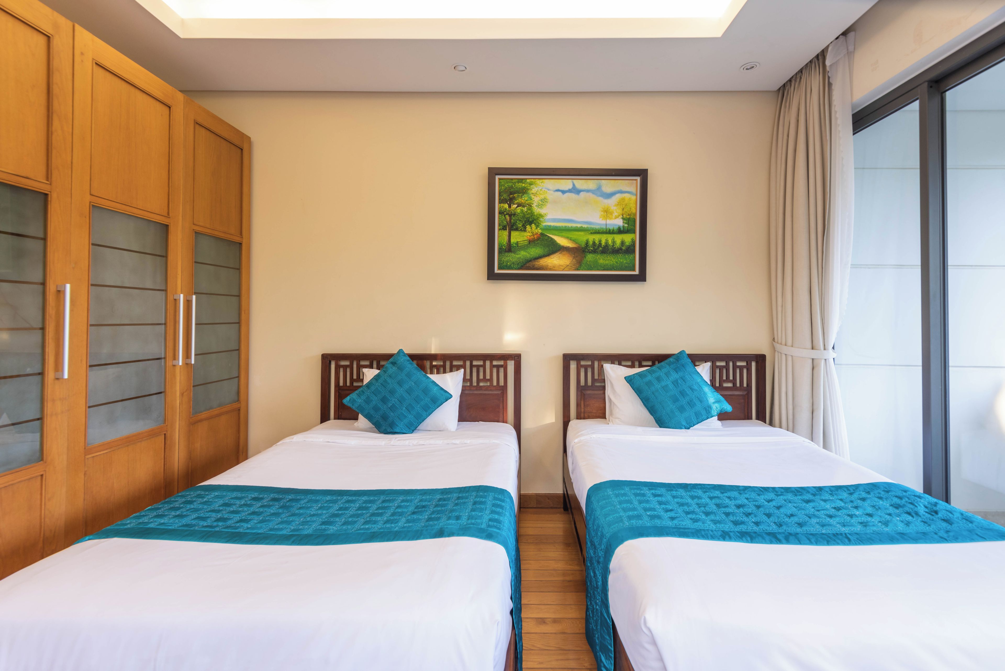 Habitación de hotel con dos camas, un cuadro en la pared y un ventanal con cortinas.
