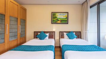 Habitación de hotel con dos camas, un cuadro en la pared y un ventanal con cortinas.
