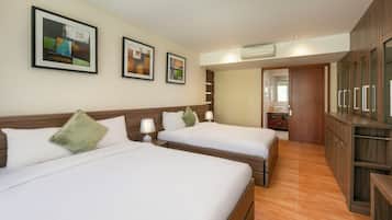 Habitación de hotel con dos camas, un armario de madera y cuadros en la pared.