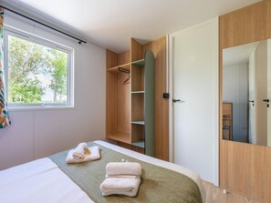 A hotel room with a bed, a wardrobe, and a mirror. - New Vennepark Caravan 463 (De Haan)