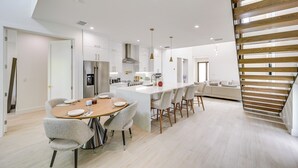A modern kitchen with white cabinetry, a central island, and pendant lighting.