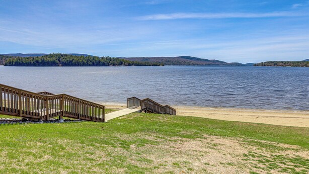 Vista al lago con muelle de madera que da a una playa arenosa.