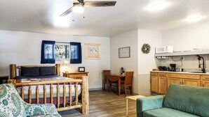 Habitación compacta con cama, sofá, mesa de comedor y kitchenette.