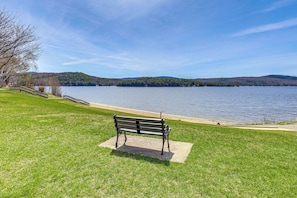 Un banco junto a un lago, con vistas claras al agua y colinas lejanas.