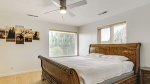 Ein Schlafzimmer mit einem hölzernen Bett, einem Deckenventilator und einem großen Fenster.