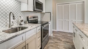 A kitchen with white cabinets, a stainless steel sink, a microwave, and an oven. - Water-View Patio! Condo 2 Mi to Surfside Beach (Myrtle Beach)