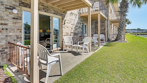 A building with a brick facade, outdoor seating area with white chairs, and a palm tree. - Water-View Patio! Condo 2 Mi to Surfside Beach (Myrtle Beach)