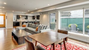Ein modernes Wohnzimmer mit einem Ecksofa, einem Holztisch und einem Esstisch mit Stühlen.