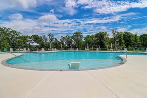 A swimming pool with a curved edge, surrounded by lounge chairs and umbrellas, under a clear sky. - Near Slopes, Trails & Fun! Camelback Townhome (Tannersville)