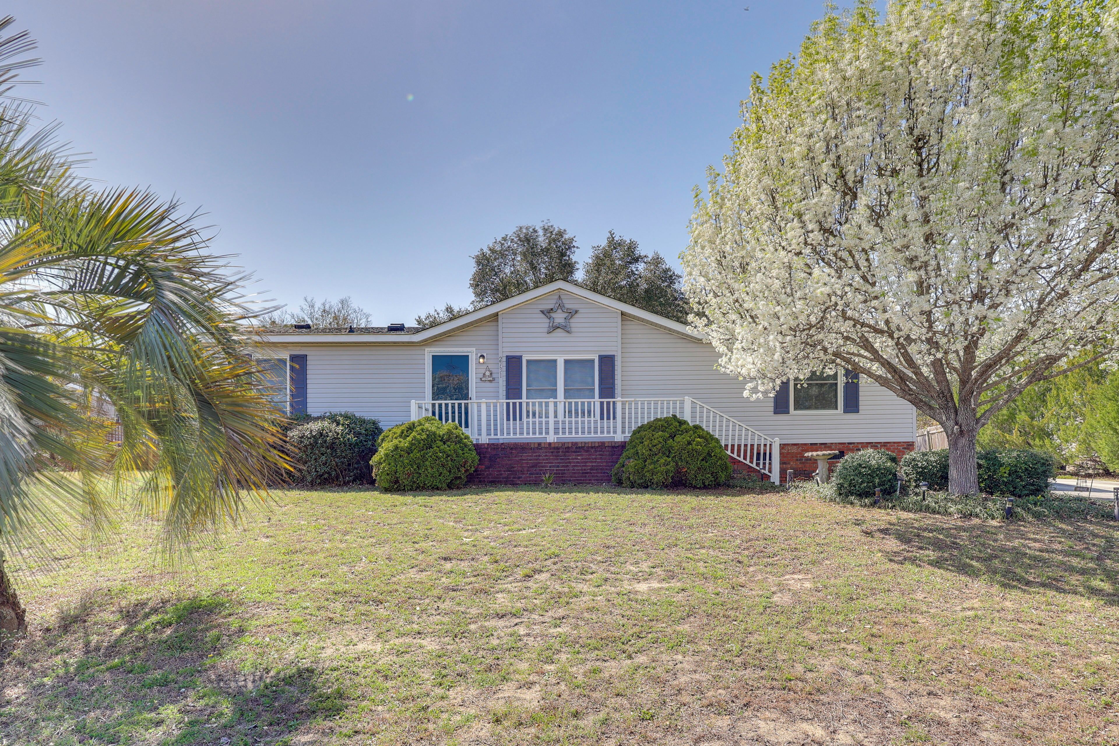 A single-story house with a front porch, a star on the roof, and a tree with white blossoms.