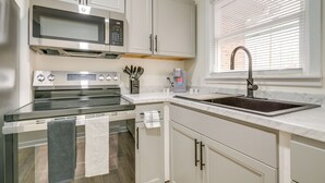 Een moderne keuken met een inbouwmagnetron, oven en een roestvrijstalen spoelbak.