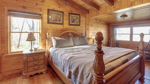 Ein Schlafzimmer einer Holzhütte mit Bett, Nachttisch, Lampe und gerahmten Bildern an der Wand.