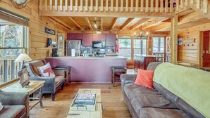 Ein Holzblockhaus Innenansicht mit Wohnbereich, Küche und Esstisch.