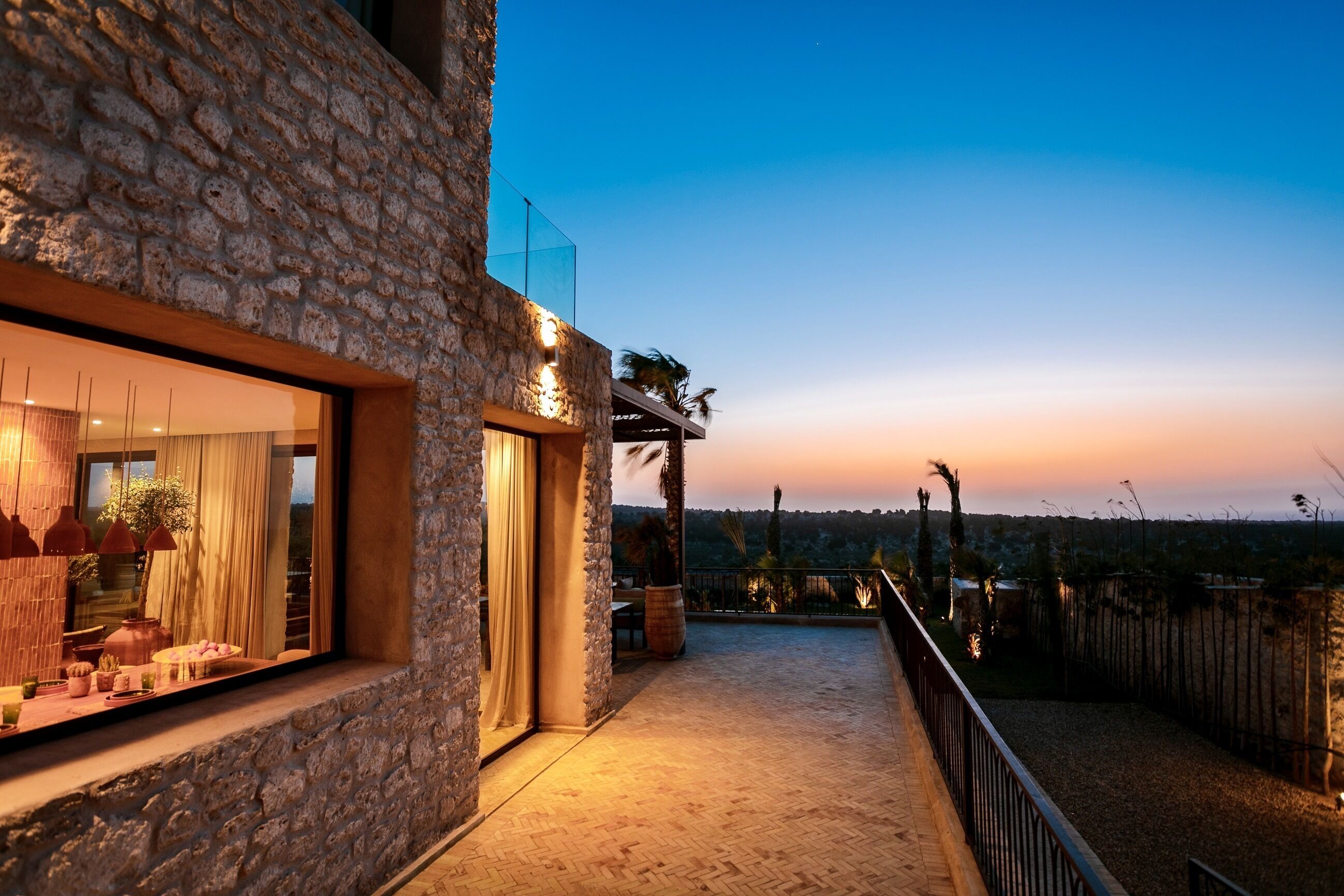 Un edificio de piedra con un balcón y vistas al paisaje, con un atardecer.