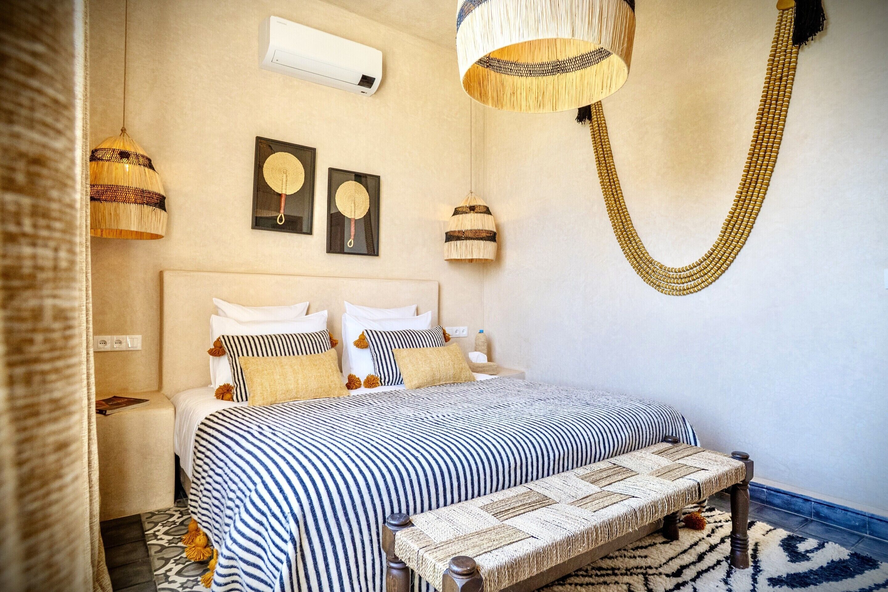 Un dormitorio con cama, mesitas de noche, una lámpara colgante y decoración en la pared.