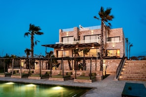Un edificio moderno con piscina, mobiliario de exterior y palmeras.