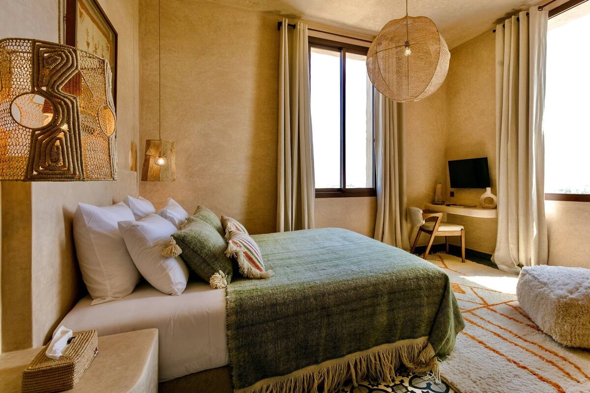 Un dormitorio con cama, escritorio, televisor y ventana grande.