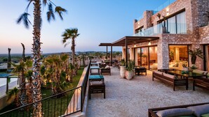 Un patio moderno al aire libre con mobiliario, piscina y vistas al paisaje.